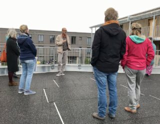 Unser Architekt erklärt Interessenten das Gebäude. Alle stehen auf der Ebene des zukünftigen Dachgartens. Blick auf den Architekten die Zuschauer in Rückenansicht.